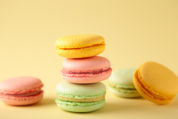 A vertical stack of three macarons on beige background. Sweet dessert
