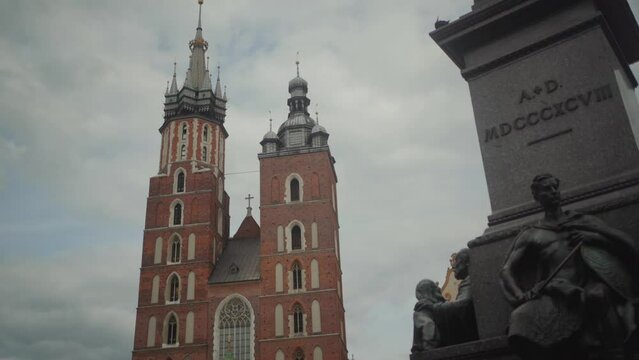 Revealing shot of Bugle Tower from the Adam Mickiewicz Monument in the Kraków, Poland