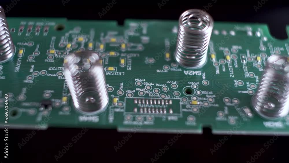 Poster close up view of springs on underside of a computer circuit chip board. dolly left