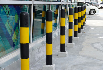 Yellow traffic bollards in front of glass wall at shopping mall 
