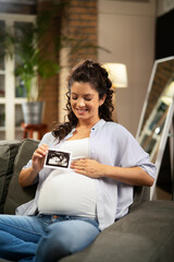  Pregnant woman with ultrasound photo. Beautiful pregnant woman enjoy at home.