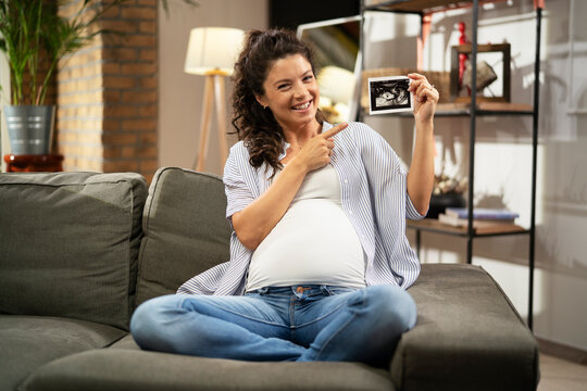  Pregnant woman with ultrasound photo. Beautiful pregnant woman enjoy at home.