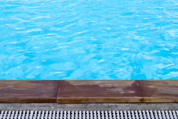 Blue swimming pool and wood plank edge on background