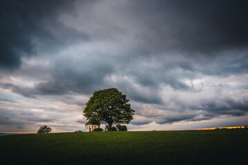 Kapelle mit Baum und dramatischen Wolken auf einem H&uuml;gel in der Oberpfalz, Bayern
