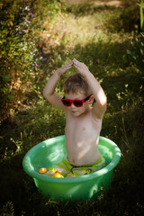 boy playing in a bowl of water in the garden