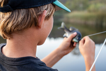 Teenage boy getting fish off the hook