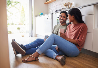 Couple communication, love with coffee in the kitchen and happy together to bond in the morning. Man and woman in India on floor, smile while in conversation and romance and healthy relationship.
