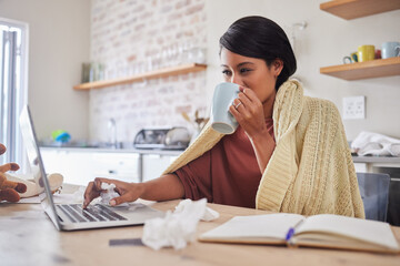 Working from home, a woman sick with covid virus or flu and doing business email with laptop on the...