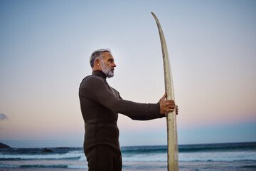 Surfer, surfboard and senior man at the beach during sunset after surfing on the waves in the sea...