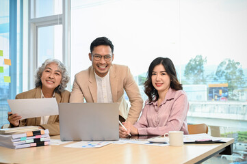 Successful Asian businesspeople in the meeting room, smiling and looking at the camera.