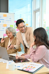 Cheerful Asian businessman discussing with a female employee during the meeting.