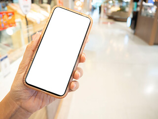 Closes-up hand holding mobile screen smartphone with supermarket blurred background.