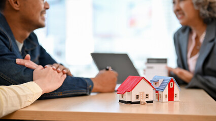 Lovely Asian couple meeting with their real estate agent or realtor to sign a lease. cropped