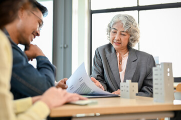 Aged Asian female executive manager in the meeting with her financial management team.
