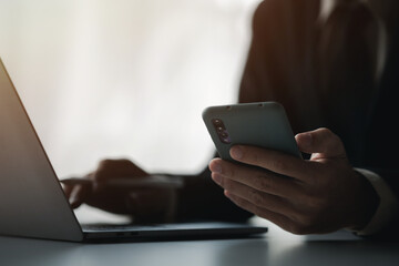 Business man looking at financial information from a mobile phone, he is checking company financial documents, he is an executive of a startup company. Concept of financial management.