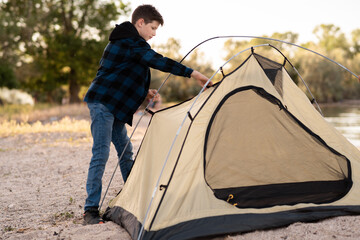 Camping people outdoor lifestyle tourists, summer river. boy installing tent. Natural children