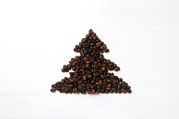 Christmas tree made of coffee beans on white wooden background