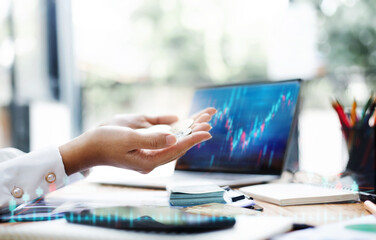 Select focus on hand, young asian businesswoman holding many coin after she success and take money from her trading and investment, Business people use laptop computer trading online and take profit