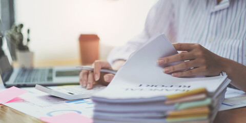 Business woman using calculator for do math finance on wooden desk in office and business working background, tax, accounting, statistics and analytic research concept