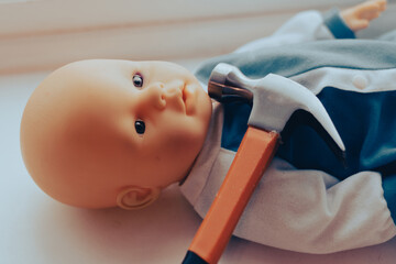baby doll with a hammer. child abuse concept