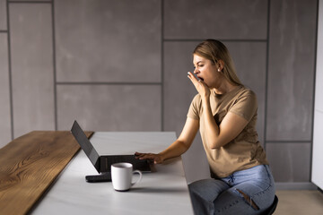 Angry shocked young woman looking at laptop screen, sitting at table in modern kitchen at home, stressed amazed female with open mouth reading bad news in email or message, financial problem