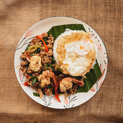 Thai Spicy pork and shrimp basil with fried egg on wood table , thai foods