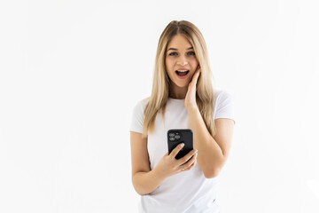 Fototapeta premium Photo of a shocked emotional surprised young woman posing isolated over white wall background using mobile phone.