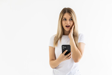 Fototapeta premium Photo of a shocked emotional surprised young woman posing isolated over white wall background using mobile phone.