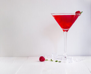 Red alcohol cocktail with raspberries and thyme on the white wood table.