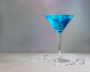 Blue cocktail in martini glass with ice cubes