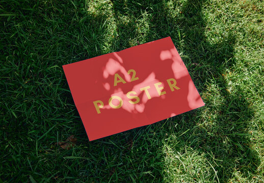 Horizontal A2 Poster Mockup Over Green Grass With Sunlight Shadows