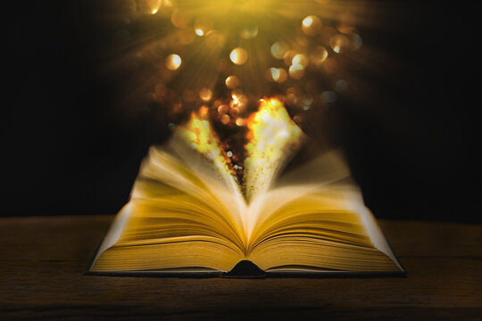 Image of an antique book open on a wooden table with vintage Fair lighting and bokeh blur abstract style background