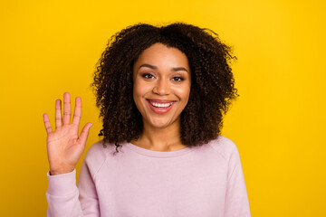Photo of young cheerful woman waving hand hello greeting symbol isolated over yellow color...