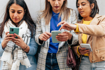 three multiethnic young ladies connected with cellphone