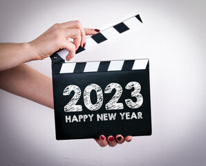 Happy New Year 2023. Female hands holding movie clapper