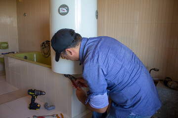 Plumber in the bathroom at home while repairing a water heater. Plumbing and DIY work

