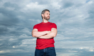 Confident guy sky background. Serious guy keeping arms crossed. Grizzled guy in casual outdoors