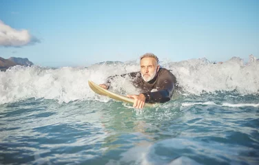 Zelfklevend Fotobehang Ocean waves, senior man surfing on beach and healthy fitness lifestyle in Australia summer holiday. Elderly surfer swimming with surfboard, sea water exercise and relax in retirement travel vacation © S Fanti/peopleimages.com