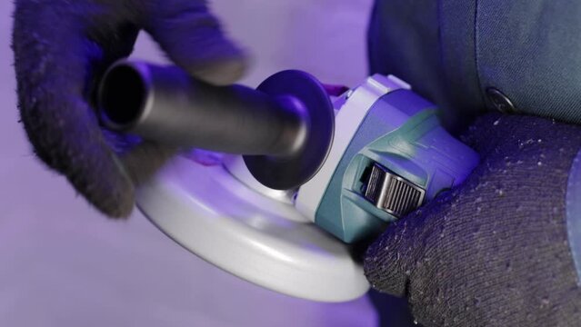 The hand twists the extra handle into the angle grinder for a comfortable grip, close-up