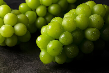 Shine Muscat with water droplets placed on black background.