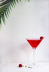 Red alcohol cocktail with raspberries and thyme on the white wood table.