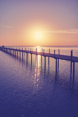 Fototapeta na wymiar Wooden pier silhouette at sunrise, color toning applied.