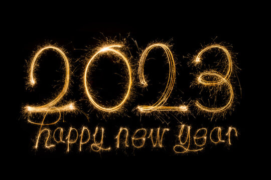 Happy New Year 2023. Sparkling burning text Happy New Year 2023 isolated on black background. Beautiful Glowing golden overlay object for design holiday greeting card