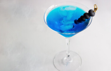 Close-up of blue cocktail in martini glass with ice cubes and bluberries