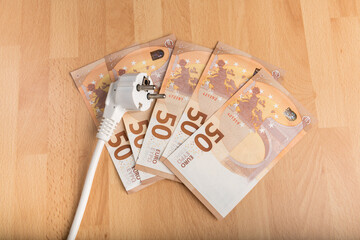 Concept energy price : electrical outlet and money on wooden background.