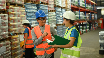 Middle age male manager and young employee checking inventory production stock control in warehouse