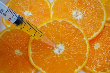 Syringe medicine put on slices round fresh orange texture background, concept mandarin, tangerine,...