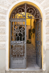 A characteristic and decorative doorway in an Italian home featuring an iron gate and stone archway.  Leads into a typical courtyard.