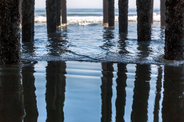Selective focus on a gentle wave under the pier at Old Orchard Beach, Maine, USA. The pillars are...
