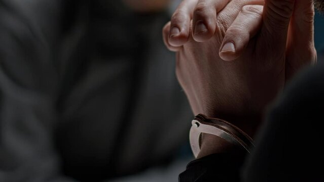 Police detective interrogates suspected criminal in handcuffs. FBI agent asks to sign confession of guilt. Detained mafia is not talking and is waiting for his lawyer. Law and justice. Innocent victim